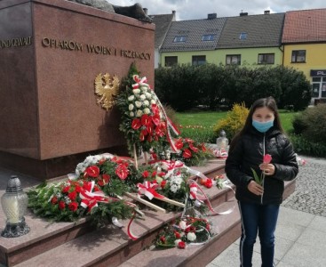 Uczennica składa kwiaty pod pomnikiem ofiar wojny - powiększ