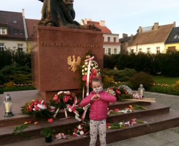 Uczennica składa kwiaty pod pomnikiem ofiar wojny - powiększ